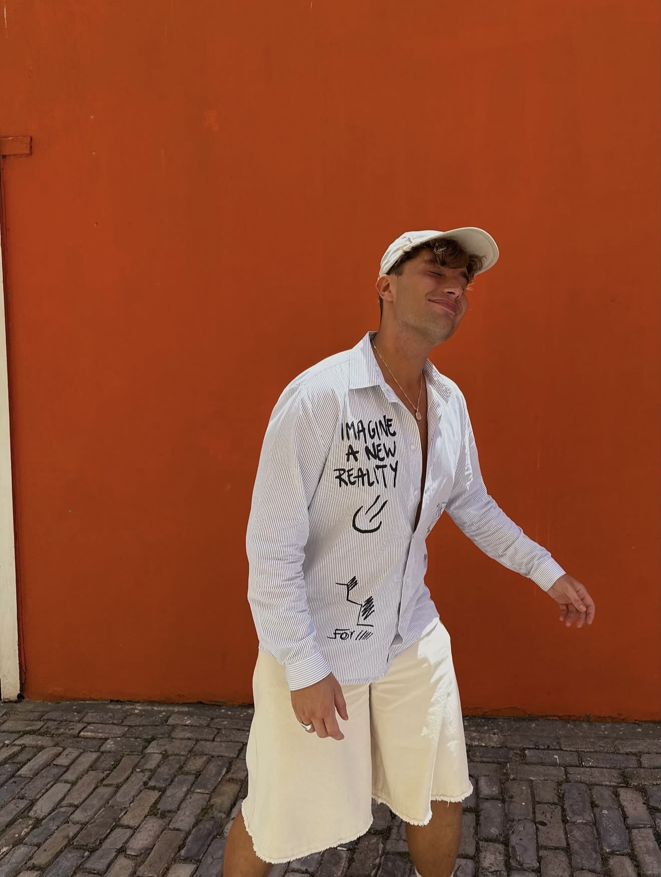 Dominik uśmiechnięty na tle pomarańczowej ściany